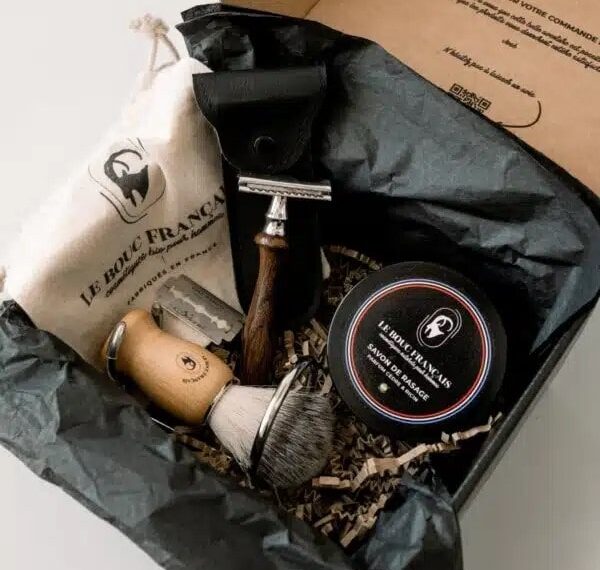 Coffret de rasage traditionnel contenant un rasoir en bois, un blaireau, du savon de rasage Le Bouc Français, et une pochette en tissu, présentés dans une boîte élégante avec des éléments d’emballage naturels.