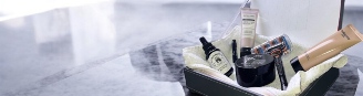 Coffret de soins pour homme contenant des produits cosmétiques, une huile pour barbe, un rasoir, une crème hydratante et divers accessoires, présentés dans une boîte élégante.